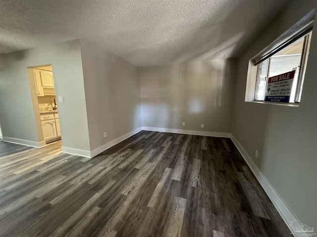 interior space with a textured ceiling, dark wood-style flooring, and baseboards