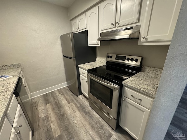 kitchen with light stone countertops, under cabinet range hood, appliances with stainless steel finishes, and white cabinets