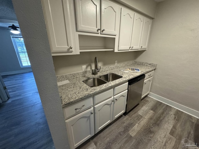 kitchen featuring a sink, white cabinets, stainless steel dishwasher, light stone countertops, and dark wood-style floors