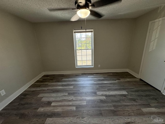 empty room with a textured ceiling, dark wood-style flooring, and baseboards