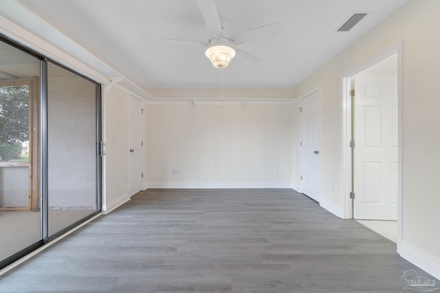 unfurnished room featuring ceiling fan, visible vents, baseboards, and wood finished floors