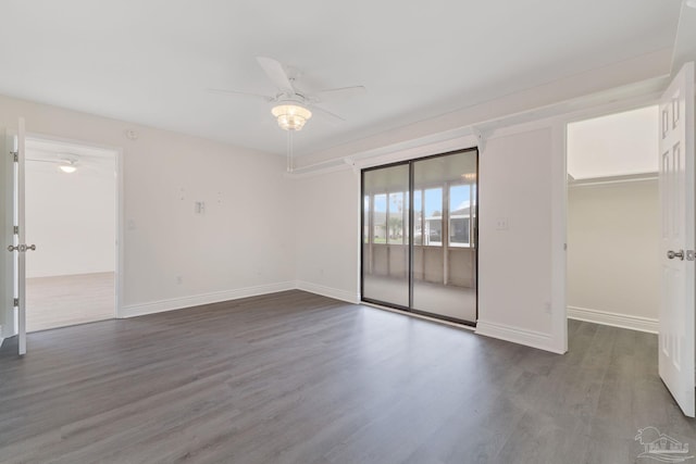 empty room featuring dark wood finished floors, baseboards, and ceiling fan