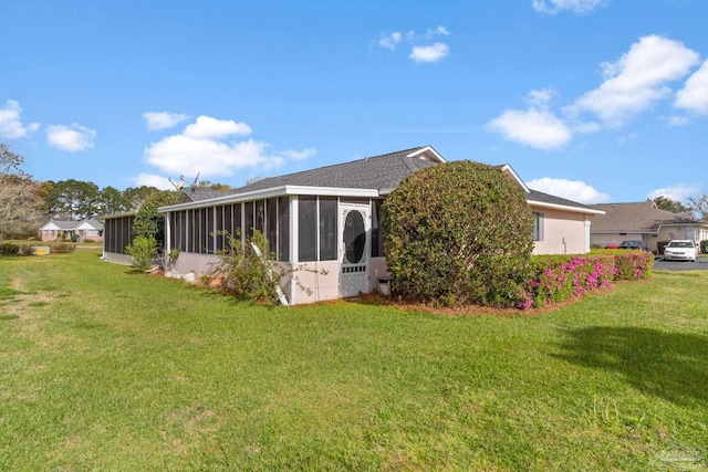 rear view of house featuring a lawn, a sunroom, and roof with shingles