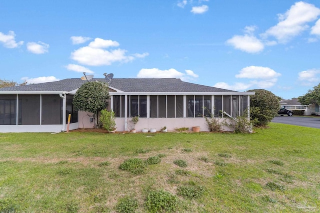 rear view of house with a yard and a sunroom