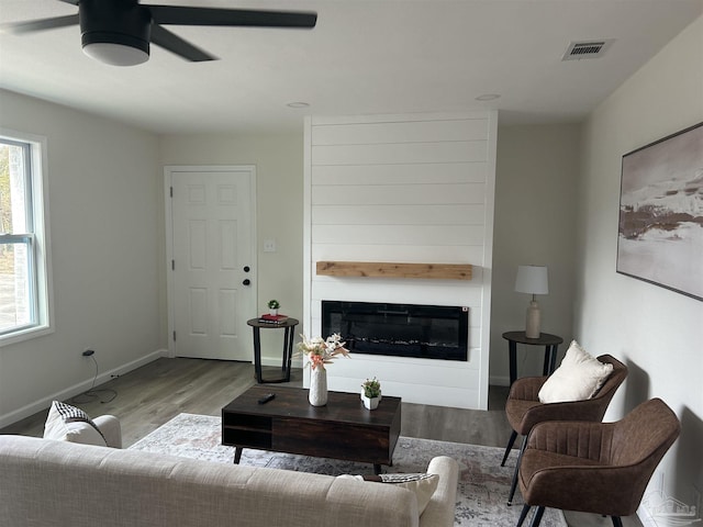 living room featuring ceiling fan, a fireplace, and light hardwood / wood-style floors