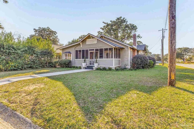 view of front of home with a sunroom and a front yard