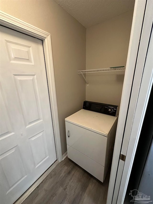 clothes washing area with washer / clothes dryer, dark hardwood / wood-style flooring, and a textured ceiling