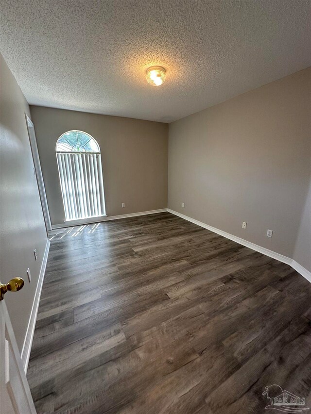 spare room with a textured ceiling and dark hardwood / wood-style flooring