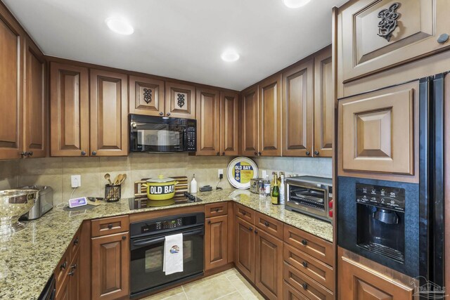 kitchen featuring light stone countertops, black appliances, tasteful backsplash, and light tile patterned floors