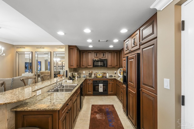 kitchen featuring light stone counters, a peninsula, a sink, black appliances, and crown molding
