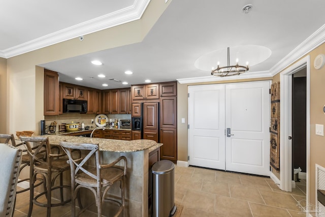 kitchen with a peninsula, black microwave, ornamental molding, and decorative light fixtures