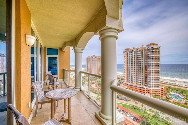 balcony with a water view and a view of the beach
