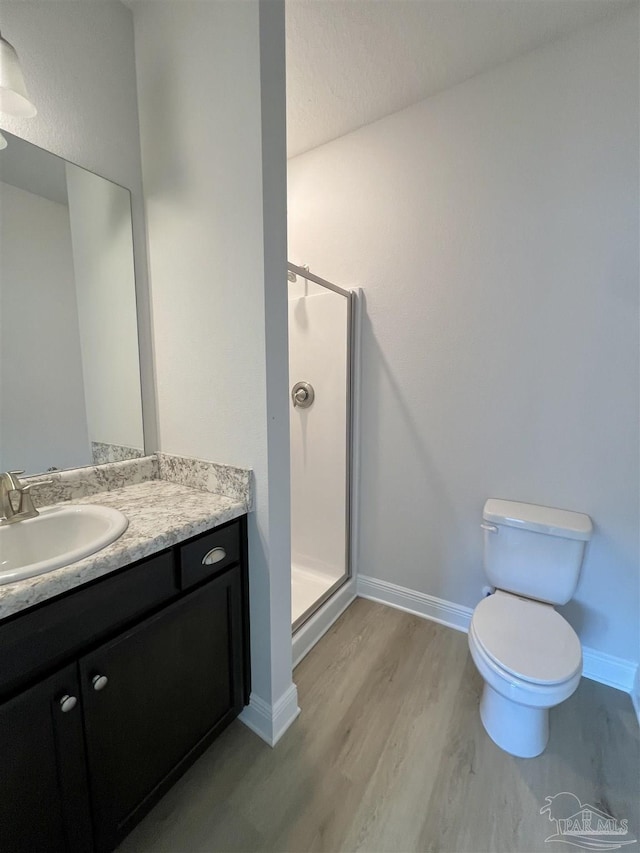 bathroom with an enclosed shower, vanity, hardwood / wood-style floors, and toilet