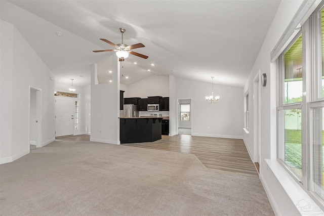 living room featuring ceiling fan with notable chandelier, a healthy amount of sunlight, and light colored carpet