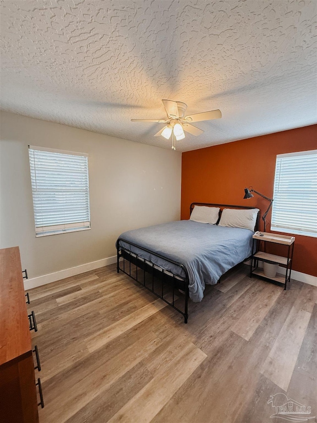 bedroom featuring hardwood / wood-style floors, ceiling fan, and a textured ceiling