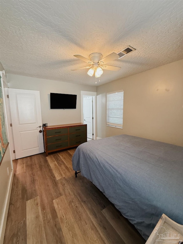 bedroom with a textured ceiling, hardwood / wood-style flooring, and ceiling fan