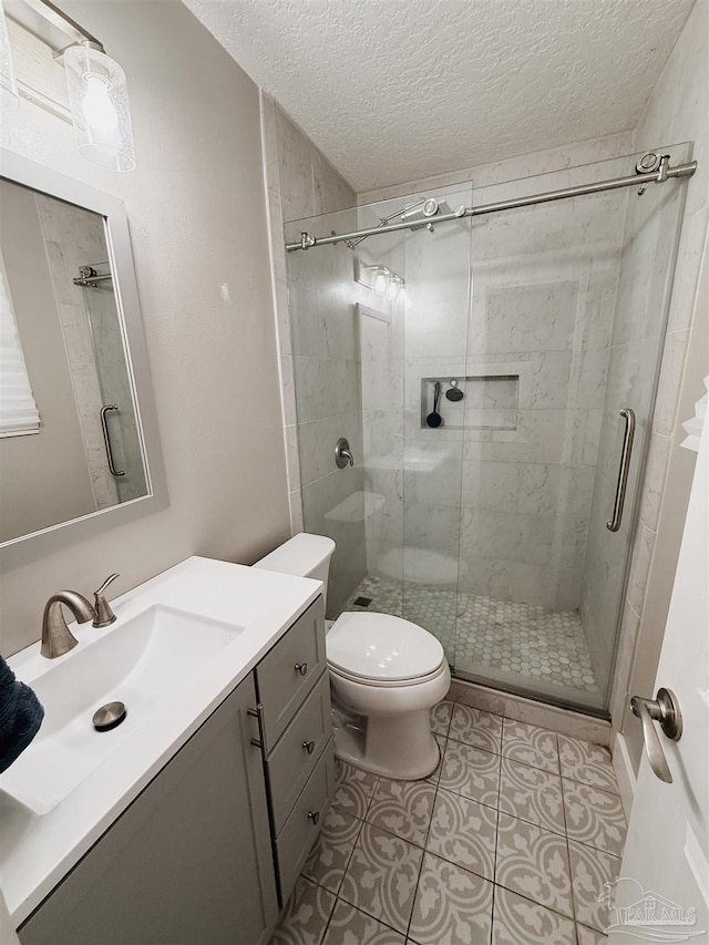 bathroom featuring toilet, a textured ceiling, tile patterned floors, and a shower with shower door