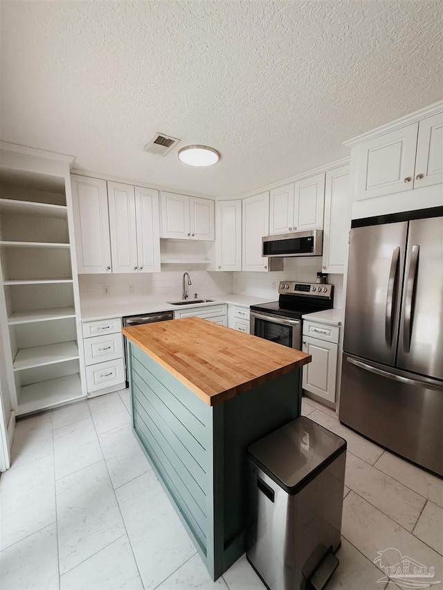 kitchen featuring sink, white cabinets, stainless steel appliances, and wood counters