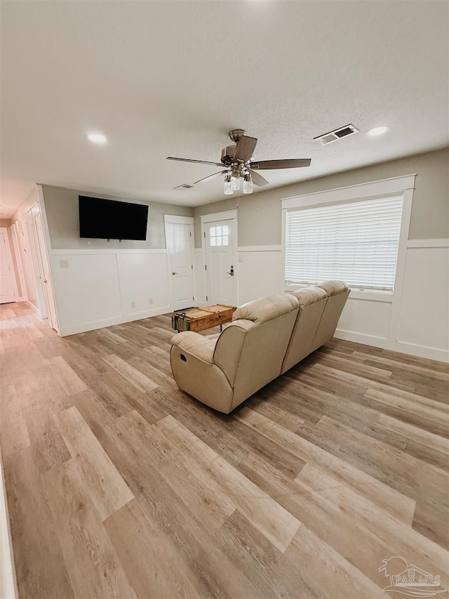 unfurnished living room with a textured ceiling, light hardwood / wood-style floors, and ceiling fan