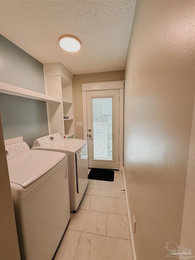 laundry room with washing machine and clothes dryer and a textured ceiling