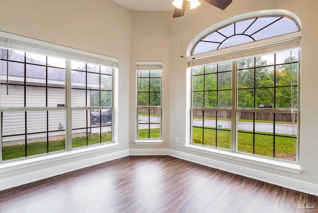 interior space with ceiling fan, baseboards, dark wood-style floors, and plenty of natural light