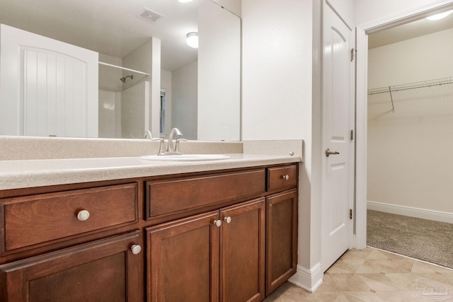 full bathroom with walk in shower, vanity, baseboards, and visible vents