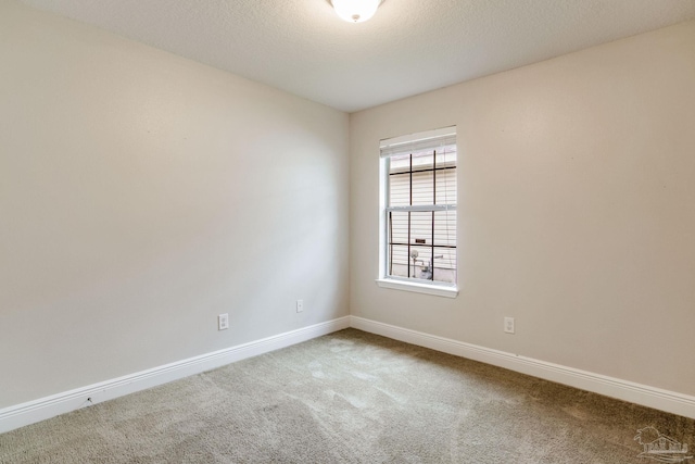 carpeted empty room with a textured ceiling and baseboards
