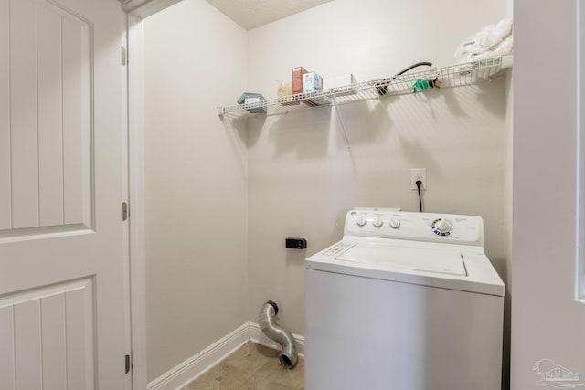 clothes washing area with washer / clothes dryer, light tile patterned floors, laundry area, and baseboards