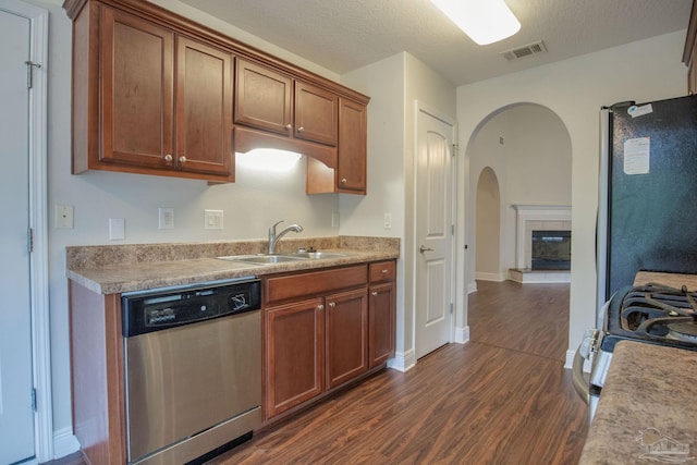 kitchen with visible vents, arched walkways, a sink, dark wood-style flooring, and appliances with stainless steel finishes