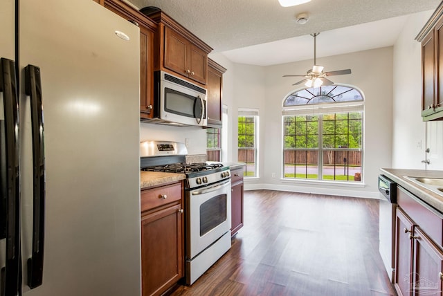 kitchen with baseboards, dark wood-style flooring, appliances with stainless steel finishes, a ceiling fan, and a textured ceiling