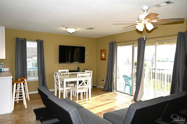 living room with a healthy amount of sunlight, a textured ceiling, light tile patterned floors, and ceiling fan