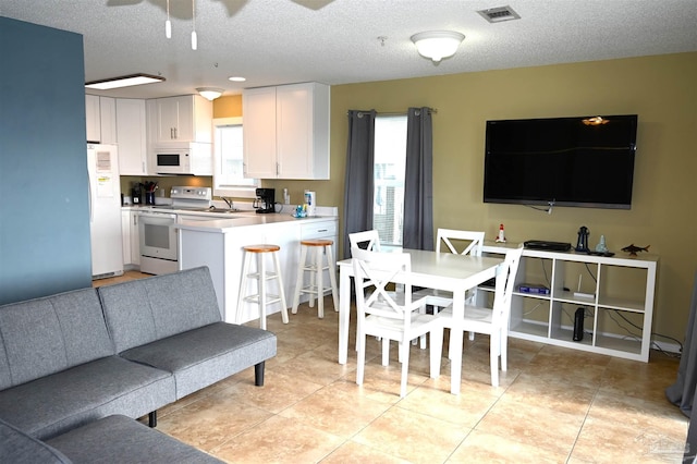 interior space featuring ceiling fan, sink, light tile patterned floors, and a textured ceiling