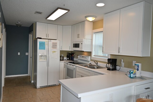 kitchen featuring light tile patterned flooring, white cabinets, white appliances, and kitchen peninsula