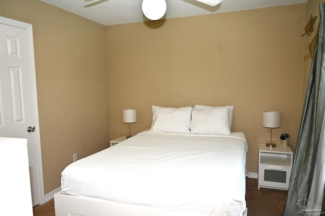 bedroom featuring a textured ceiling, dark colored carpet, and ceiling fan