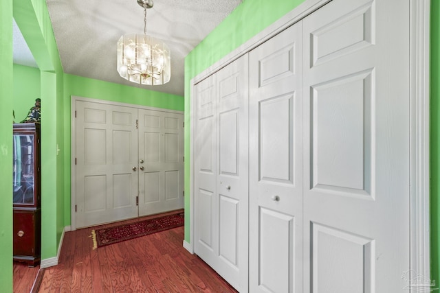 foyer featuring dark hardwood / wood-style floors, a textured ceiling, and an inviting chandelier