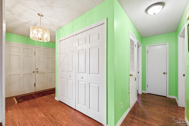 hallway with hardwood / wood-style floors, a notable chandelier, and a textured ceiling