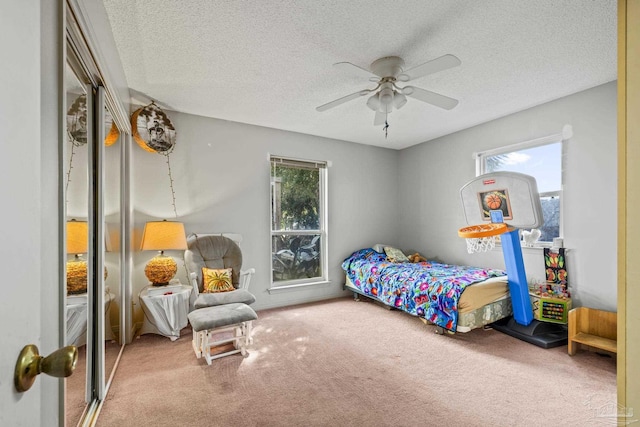 carpeted bedroom featuring a textured ceiling and ceiling fan