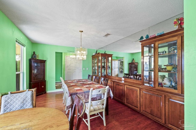 dining space featuring a chandelier, a textured ceiling, and dark hardwood / wood-style flooring