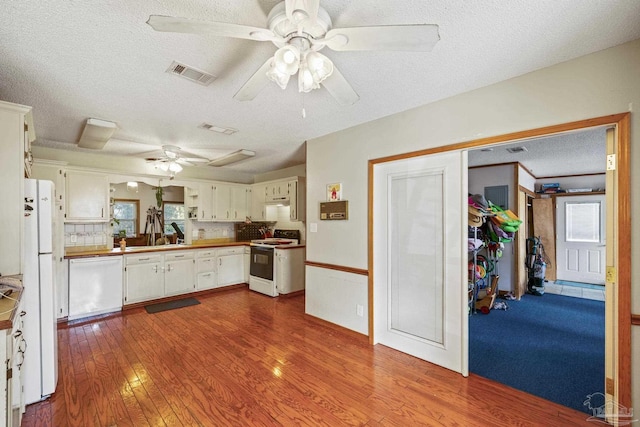 kitchen featuring white appliances, a textured ceiling, ceiling fan, hardwood / wood-style floors, and white cabinets