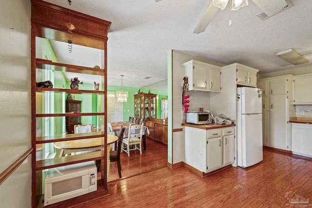 kitchen featuring pendant lighting, hardwood / wood-style floors, white appliances, and tasteful backsplash