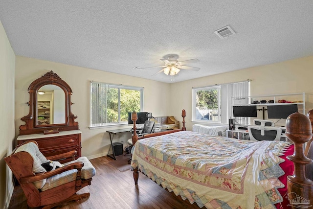 bedroom with ceiling fan, wood-type flooring, multiple windows, and a textured ceiling