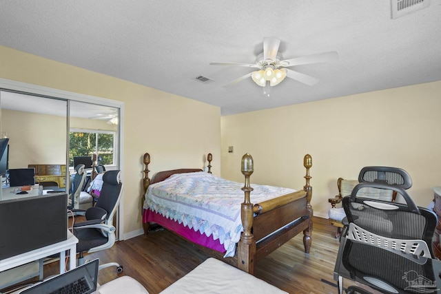 bedroom with ceiling fan, dark wood-type flooring, and a textured ceiling
