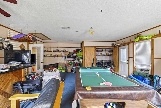 playroom featuring ornamental molding, carpet floors, washing machine and clothes dryer, and a textured ceiling