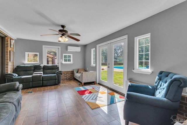 living area with ceiling fan, french doors, a wall unit AC, and wood finished floors