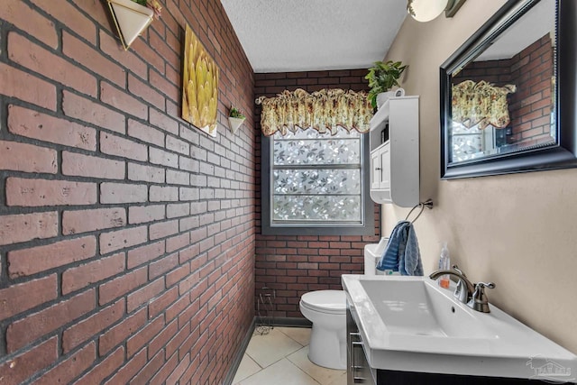 bathroom featuring tile patterned flooring, brick wall, toilet, vanity, and a textured ceiling