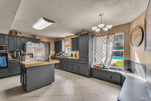 kitchen with decorative light fixtures, a sink, a center island, appliances with stainless steel finishes, and an inviting chandelier