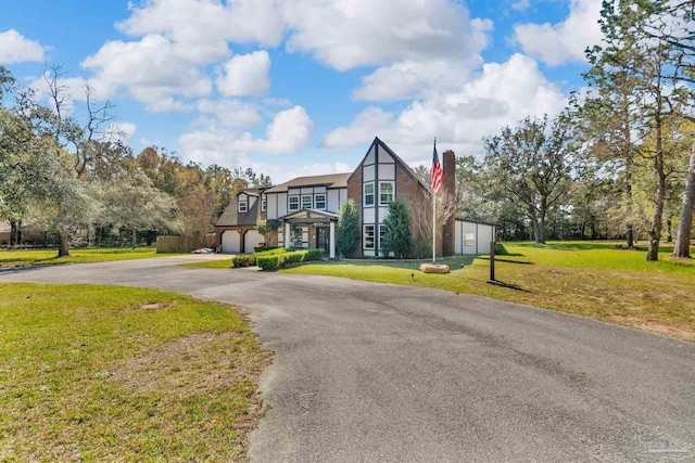 english style home featuring aphalt driveway, a garage, and a front yard