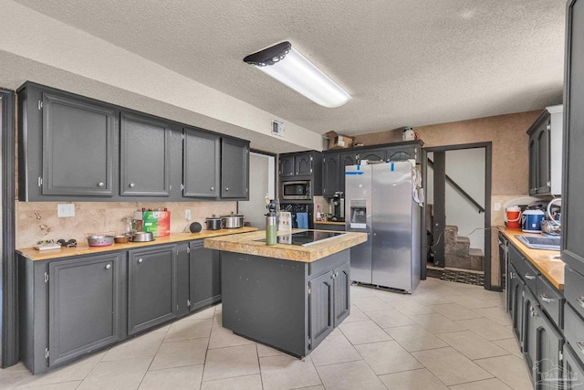 kitchen featuring light tile patterned floors, appliances with stainless steel finishes, a center island, and light countertops