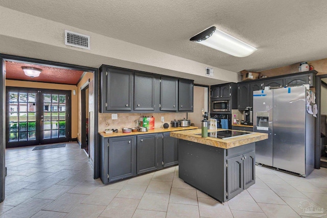 kitchen featuring visible vents, a center island, light countertops, appliances with stainless steel finishes, and french doors