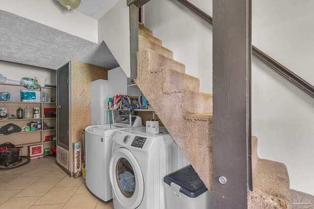 laundry area with separate washer and dryer, light tile patterned flooring, laundry area, and a textured ceiling